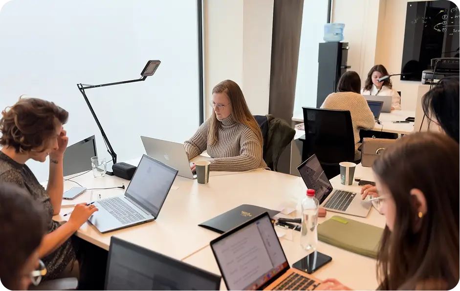 Team of professionals working together on laptops in a modern office meeting room.