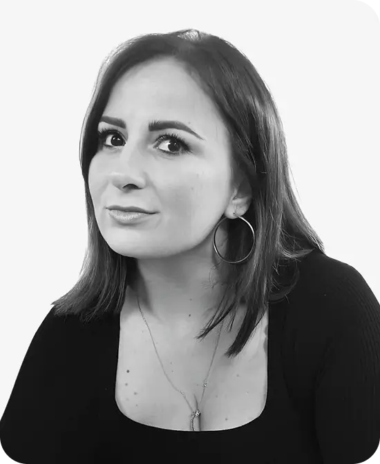 Studio portrait of a woman with shoulder-length hair, hoop earrings, and confident expression.