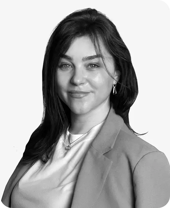 Portrait of a professional woman in a blazer, smiling confidently against a light background.