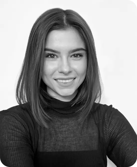 Smiling woman with straight shoulder-length hair wearing a black turtleneck, studio portrait.
