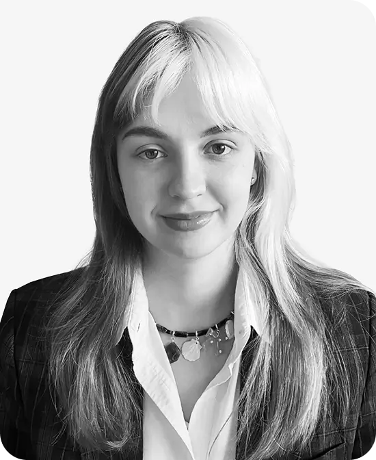 Headshot of a young woman with light hair wearing a blazer and necklace, smiling softly.